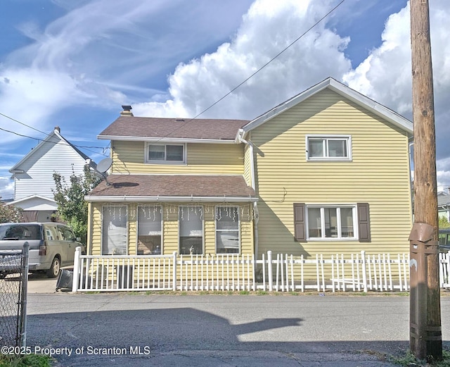 traditional home with covered porch and a fenced front yard