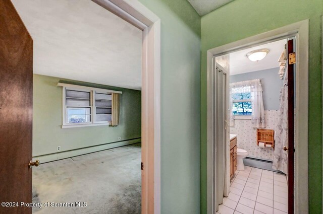 hallway with light tile patterned floors and a baseboard radiator