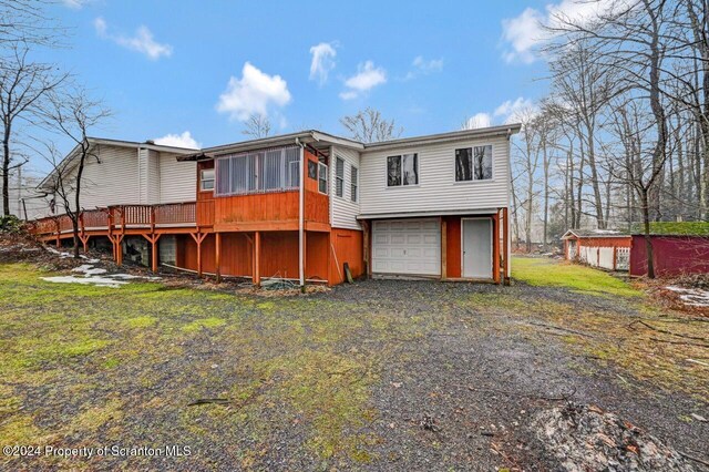 back of property with a sunroom, a deck, and a garage