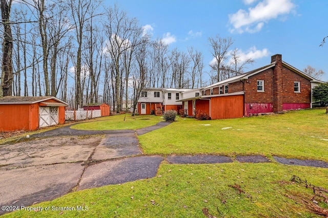 view of front of house featuring a storage unit and a front lawn