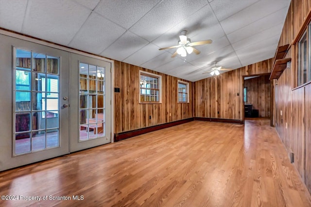 interior space with french doors, a paneled ceiling, ceiling fan, and wooden walls