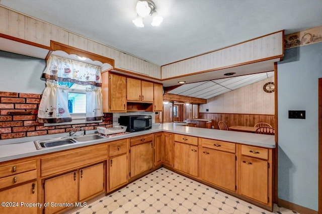 kitchen with kitchen peninsula, sink, and wooden walls