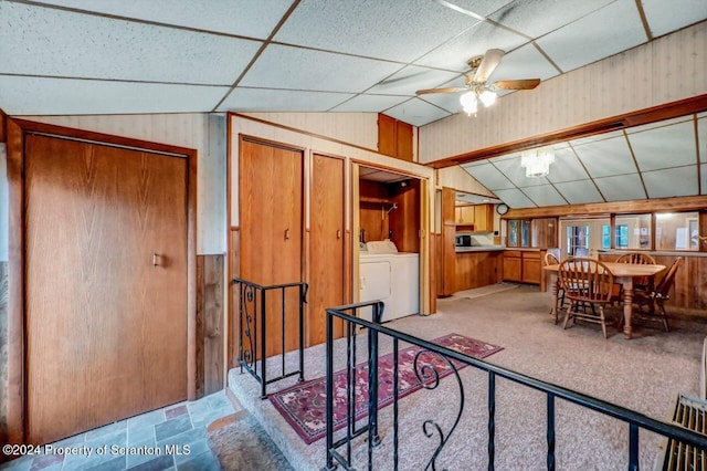 interior space with light carpet, vaulted ceiling, ceiling fan, wooden walls, and washer / clothes dryer