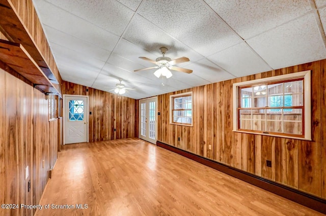 unfurnished room with wood-type flooring, a paneled ceiling, ceiling fan, and a healthy amount of sunlight