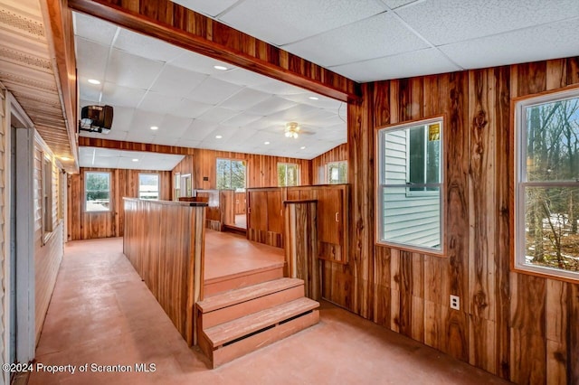 stairs with ceiling fan, a drop ceiling, and wood walls