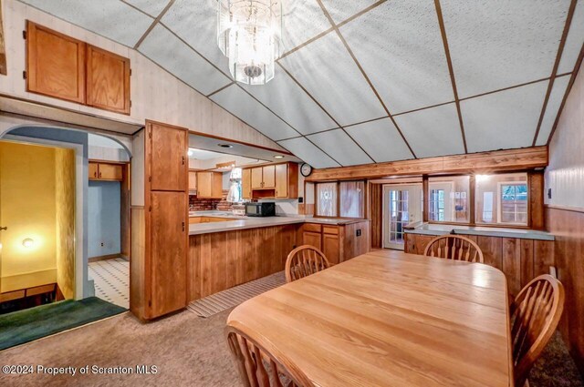 carpeted dining room featuring wooden walls