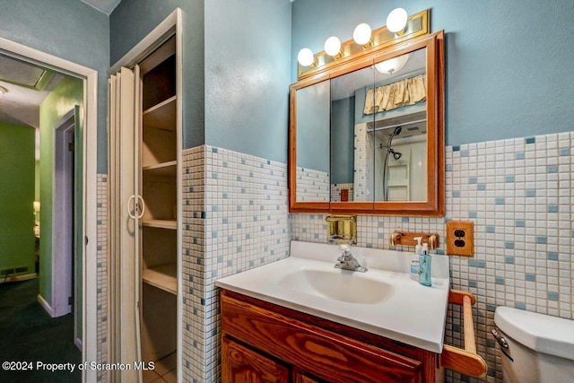 bathroom with vanity, tile walls, and toilet