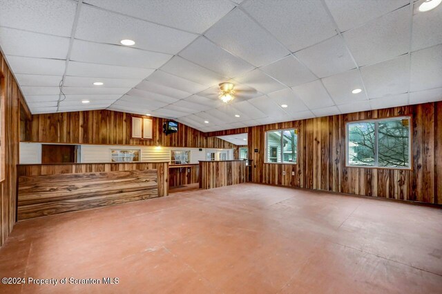 interior space featuring concrete flooring, a drop ceiling, ceiling fan, and lofted ceiling