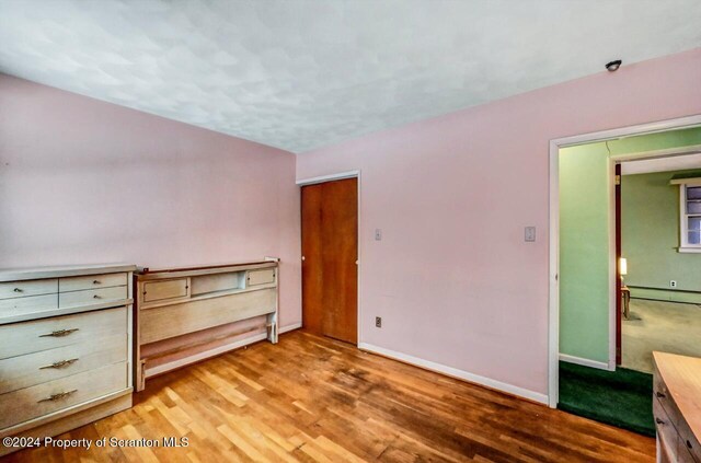 unfurnished bedroom featuring baseboard heating and light hardwood / wood-style flooring