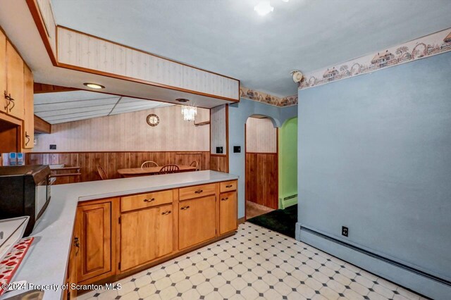 kitchen with baseboard heating and wooden walls