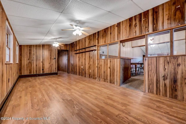 spare room featuring hardwood / wood-style flooring, a drop ceiling, wood walls, and ceiling fan