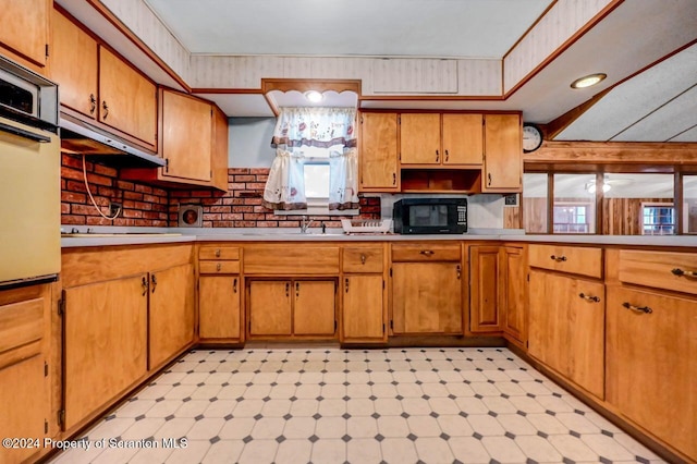 kitchen with cooktop, white oven, ceiling fan, and sink