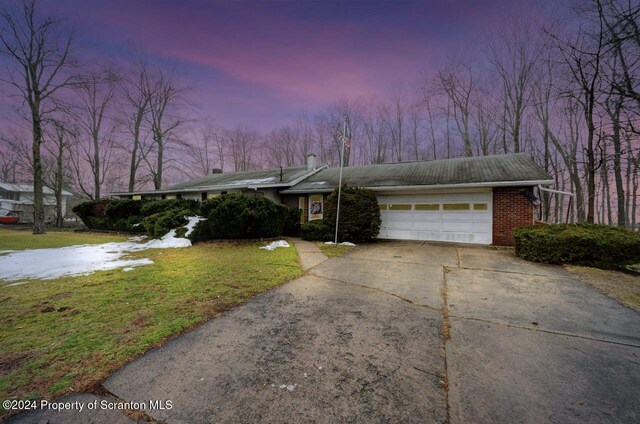 single story home featuring a lawn and a garage