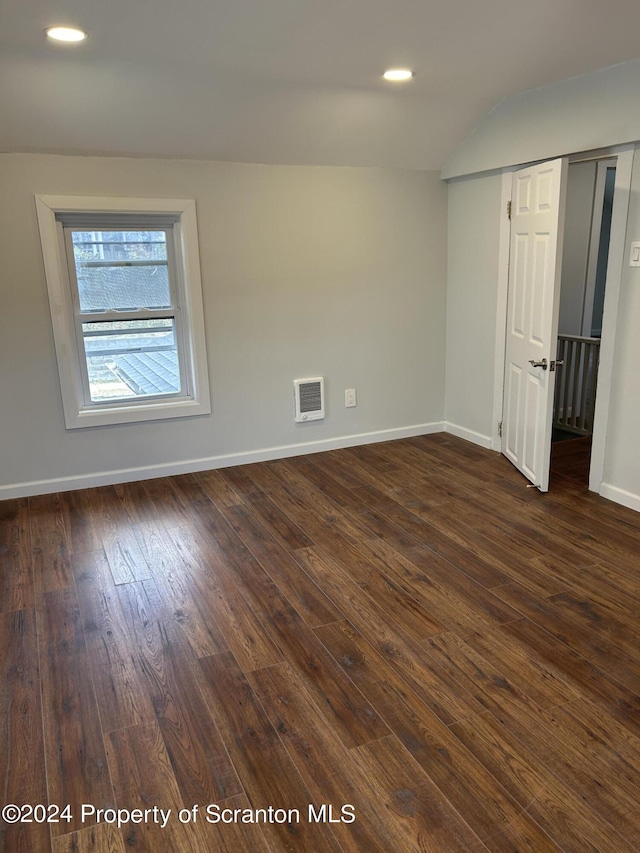 unfurnished room featuring lofted ceiling and dark hardwood / wood-style floors