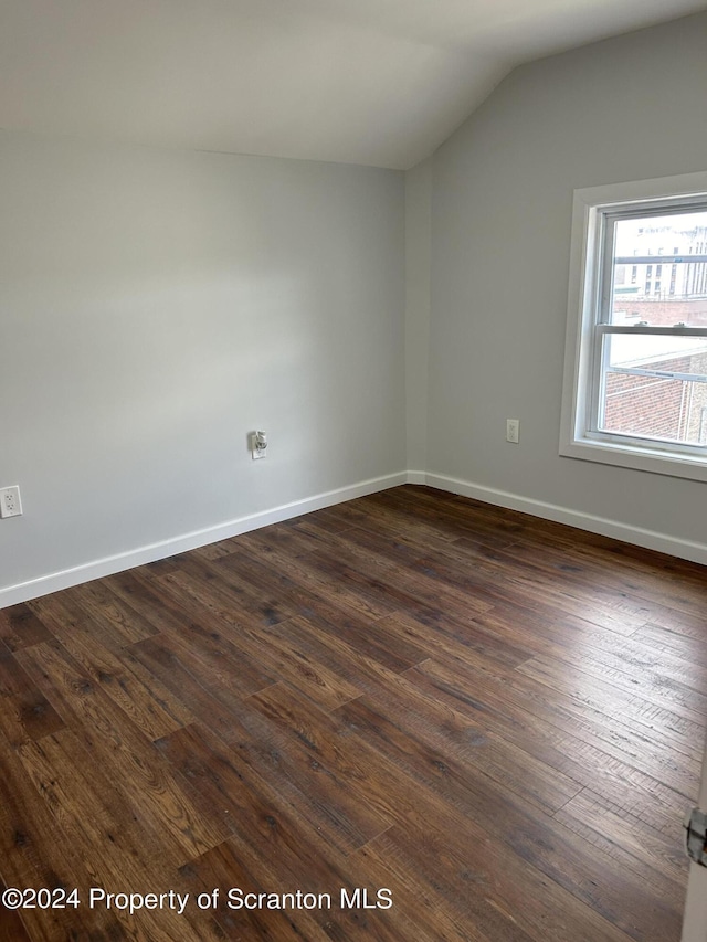 empty room with dark hardwood / wood-style floors and vaulted ceiling