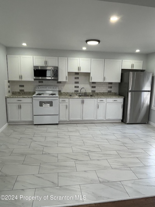 kitchen featuring dark stone countertops, white cabinetry, sink, and appliances with stainless steel finishes