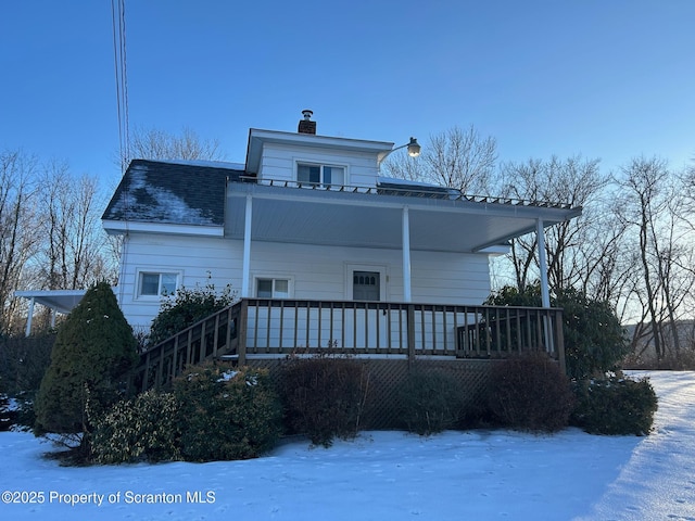 snow covered back of property with a porch