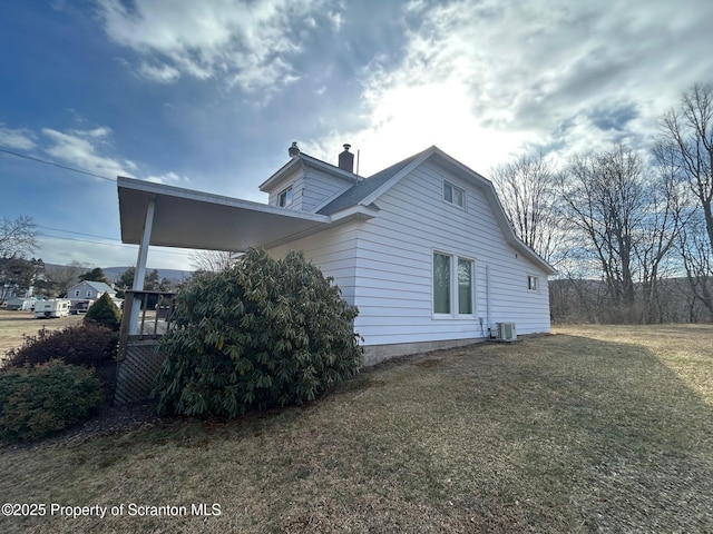 view of side of property featuring a yard and central AC unit