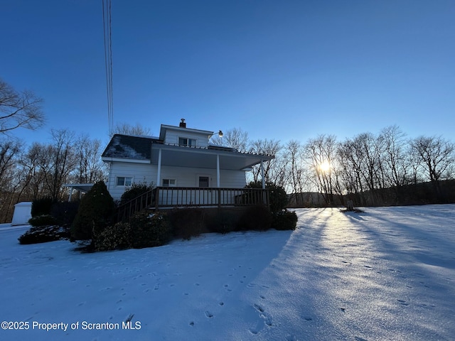 snow covered back of property with covered porch