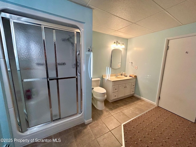 bathroom with a paneled ceiling, vanity, tile patterned floors, toilet, and walk in shower