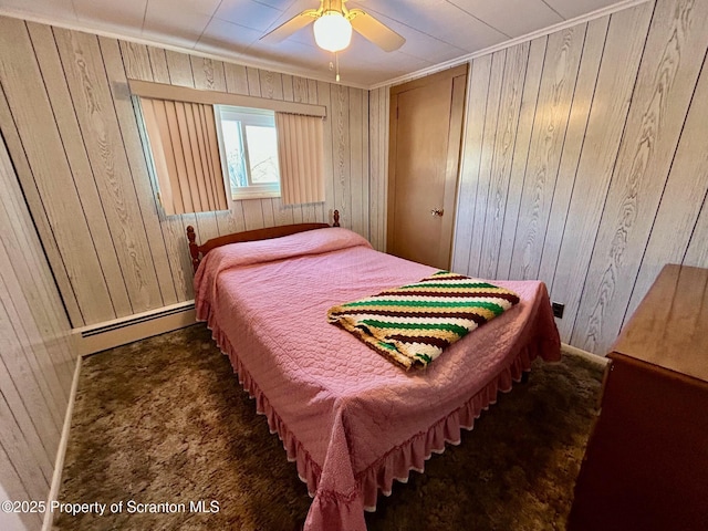 carpeted bedroom featuring baseboard heating, ceiling fan, and wood walls