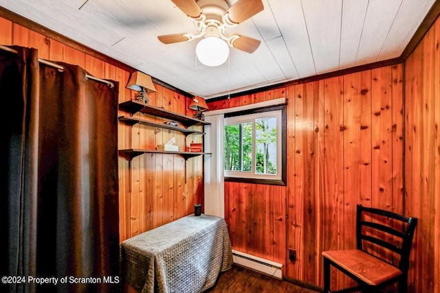 interior space with ceiling fan, dark wood-type flooring, a baseboard radiator, wooden ceiling, and wood walls