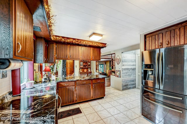 kitchen featuring dark stone countertops, light tile patterned floors, and stainless steel refrigerator with ice dispenser