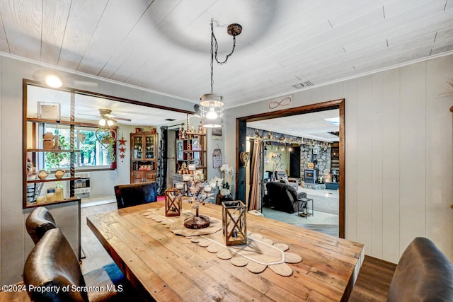 dining room featuring wooden ceiling, a wood stove, ceiling fan, and ornamental molding