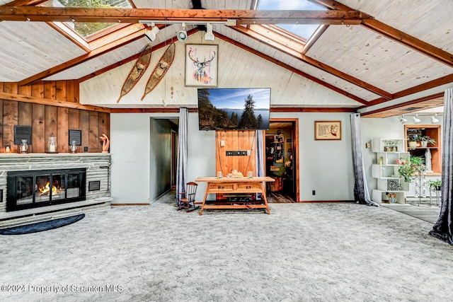 living room featuring a fireplace, carpet floors, wood walls, and vaulted ceiling with skylight