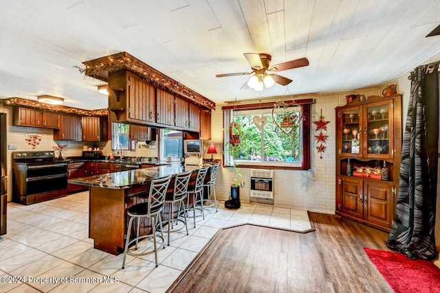 kitchen with range with electric stovetop, heating unit, plenty of natural light, and a kitchen breakfast bar