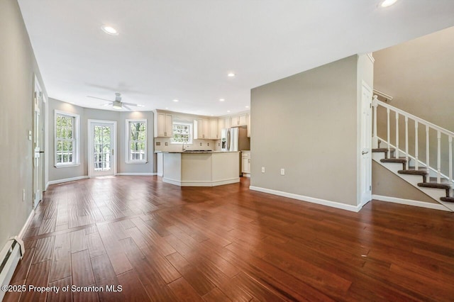 27 Emerson Dr, Moosic, PA 18507 - unfurnished living room featuring a ceiling fan, baseboard heating, dark wood-style flooring, recessed lighting, and stairs