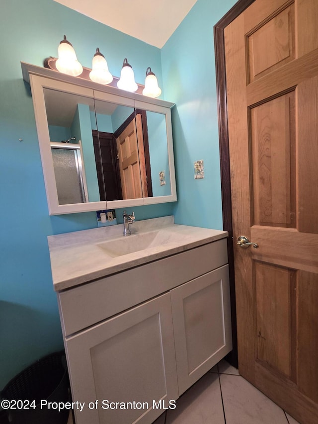 bathroom with tile patterned flooring, vanity, and walk in shower