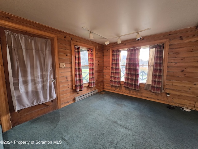 carpeted empty room featuring a baseboard radiator, track lighting, and wood walls