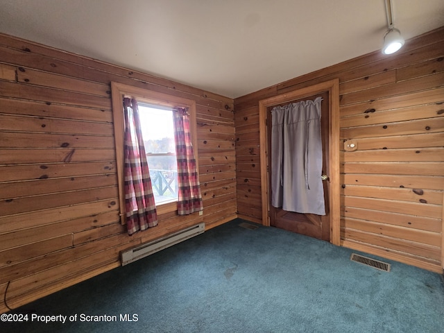 carpeted empty room featuring wooden walls and a baseboard heating unit