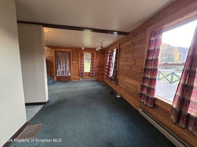 unfurnished room featuring beam ceiling, carpet floors, a baseboard radiator, and wood walls