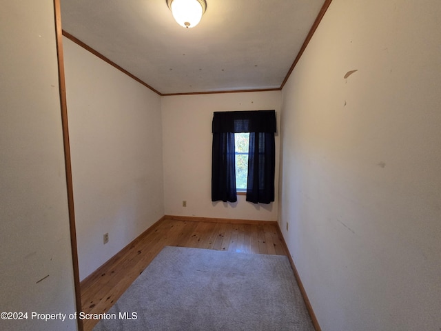 empty room with light hardwood / wood-style floors and crown molding