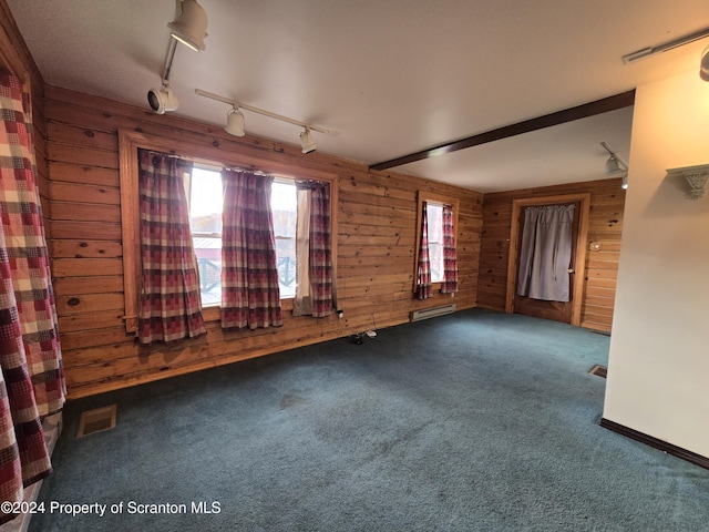 carpeted spare room with beamed ceiling and wood walls