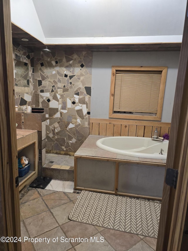 bathroom featuring a bathtub, lofted ceiling, and sink