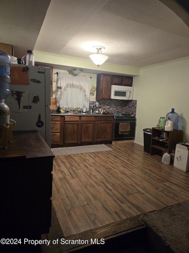 87 Grant St, Shickshinny, PA 18655 - kitchen featuring white appliances, dark countertops, light wood-style floors, arched walkways, and backsplash