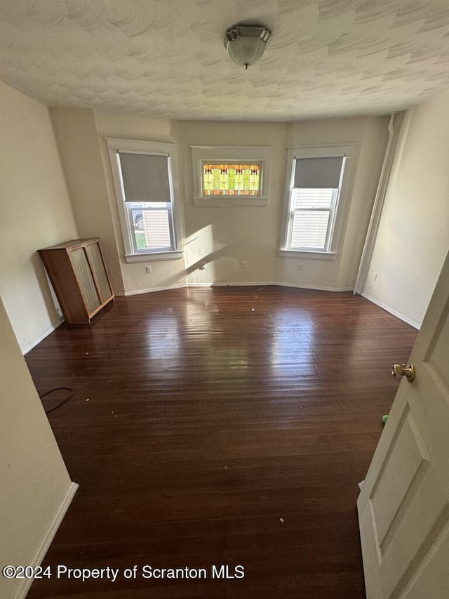 unfurnished room featuring dark wood-type flooring and a textured ceiling