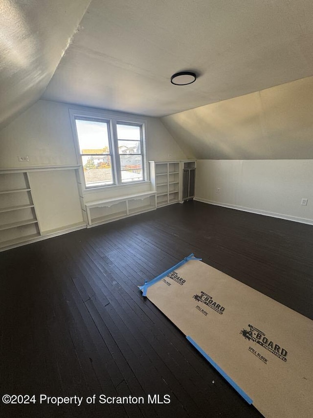 additional living space featuring dark hardwood / wood-style floors, built in features, and lofted ceiling