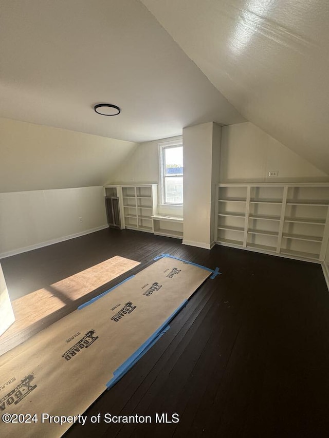 bonus room with vaulted ceiling and dark wood-type flooring