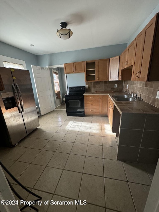 kitchen featuring sink, black electric range, stainless steel refrigerator with ice dispenser, decorative backsplash, and light tile patterned floors