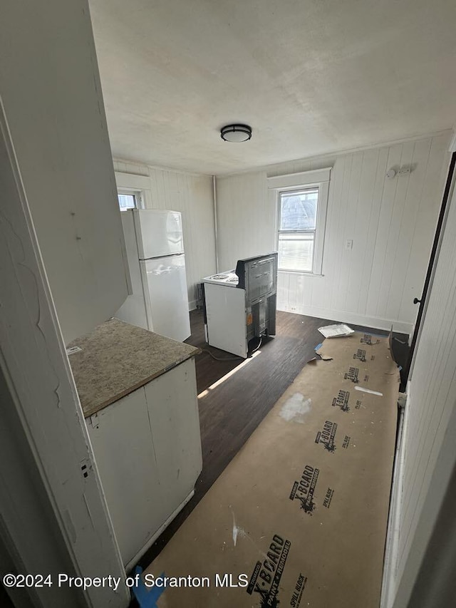 kitchen featuring white cabinets, white refrigerator, and wood walls