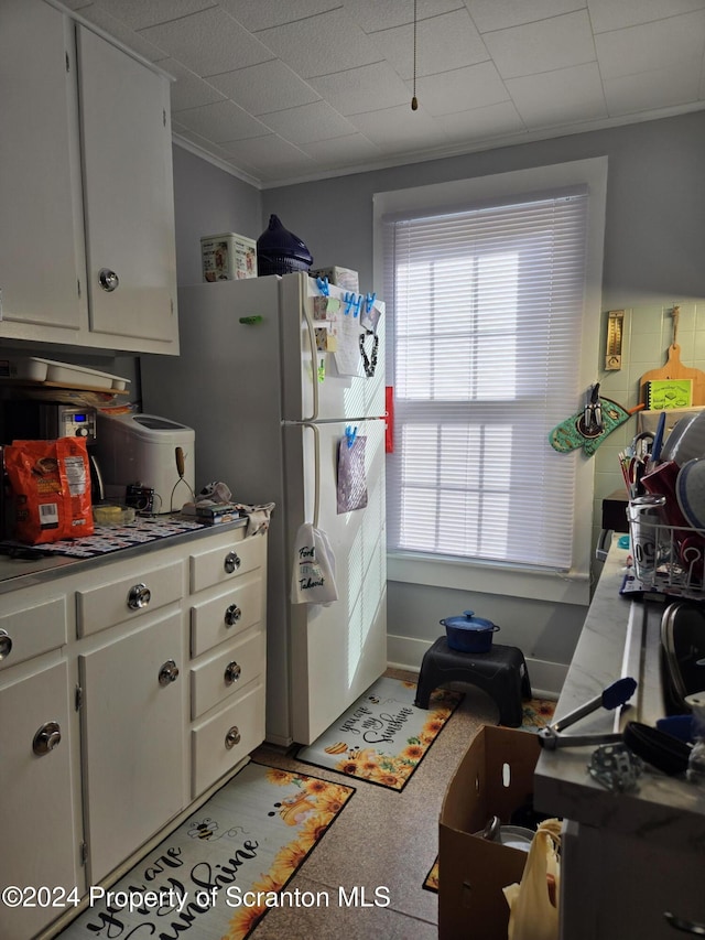 kitchen with plenty of natural light, white cabinetry, and crown molding