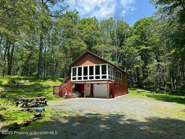 105 Hughes Dr, Greene Twp, PA 18426 - rear view of property featuring stairs, a sunroom, gravel driveway, and a wooded view