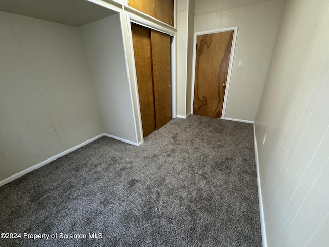 unfurnished bedroom with dark carpet and a closet