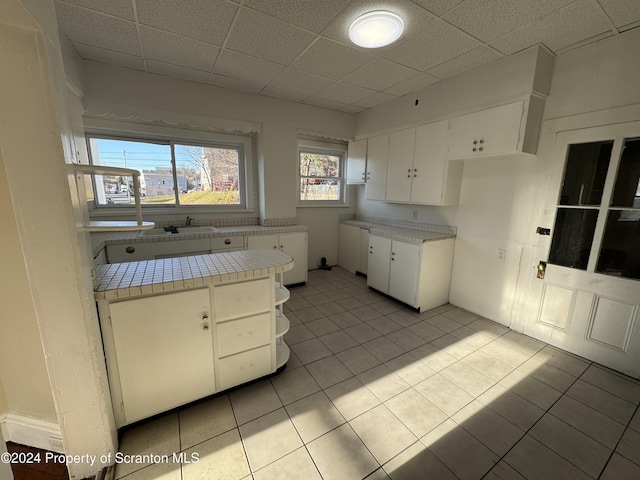 kitchen with white cabinets, tile counters, and light tile patterned floors