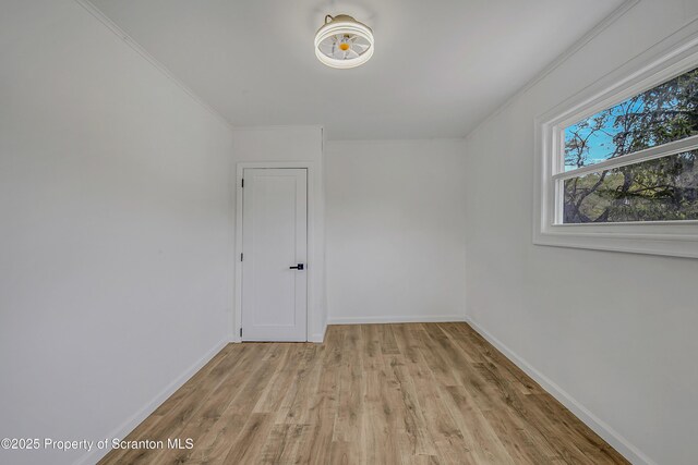 spare room featuring baseboards, ornamental molding, and light wood-type flooring