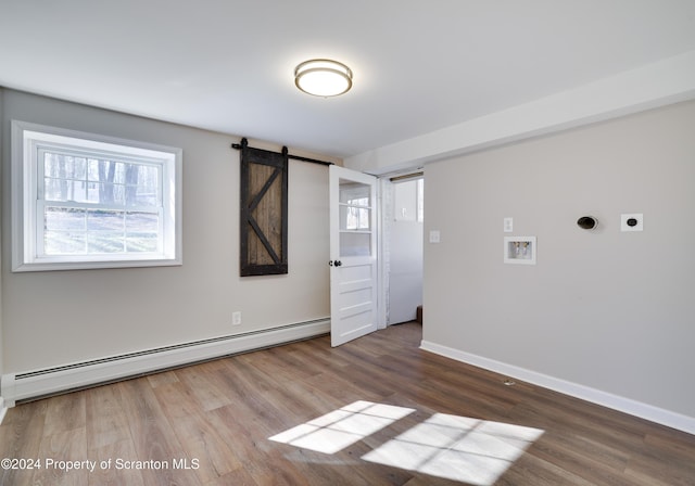 spare room with hardwood / wood-style floors, a barn door, and baseboard heating